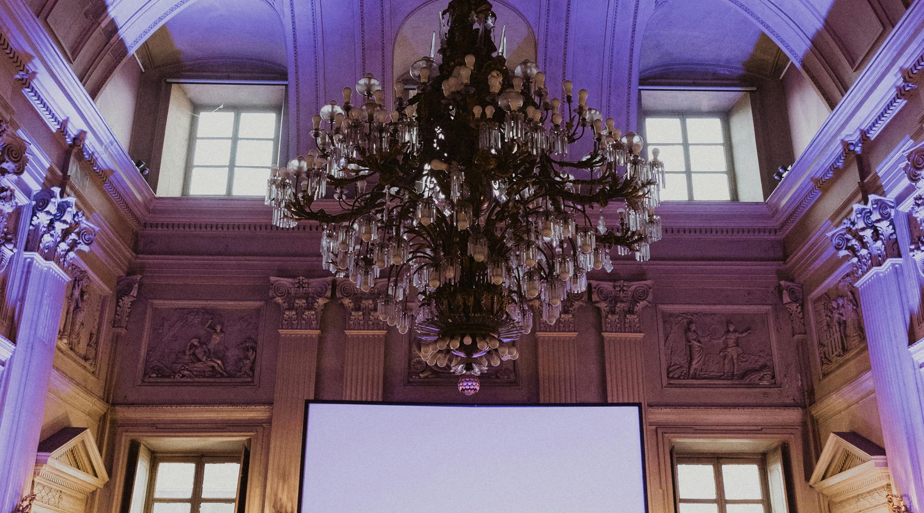 Big room with chairs, screen and chandelier