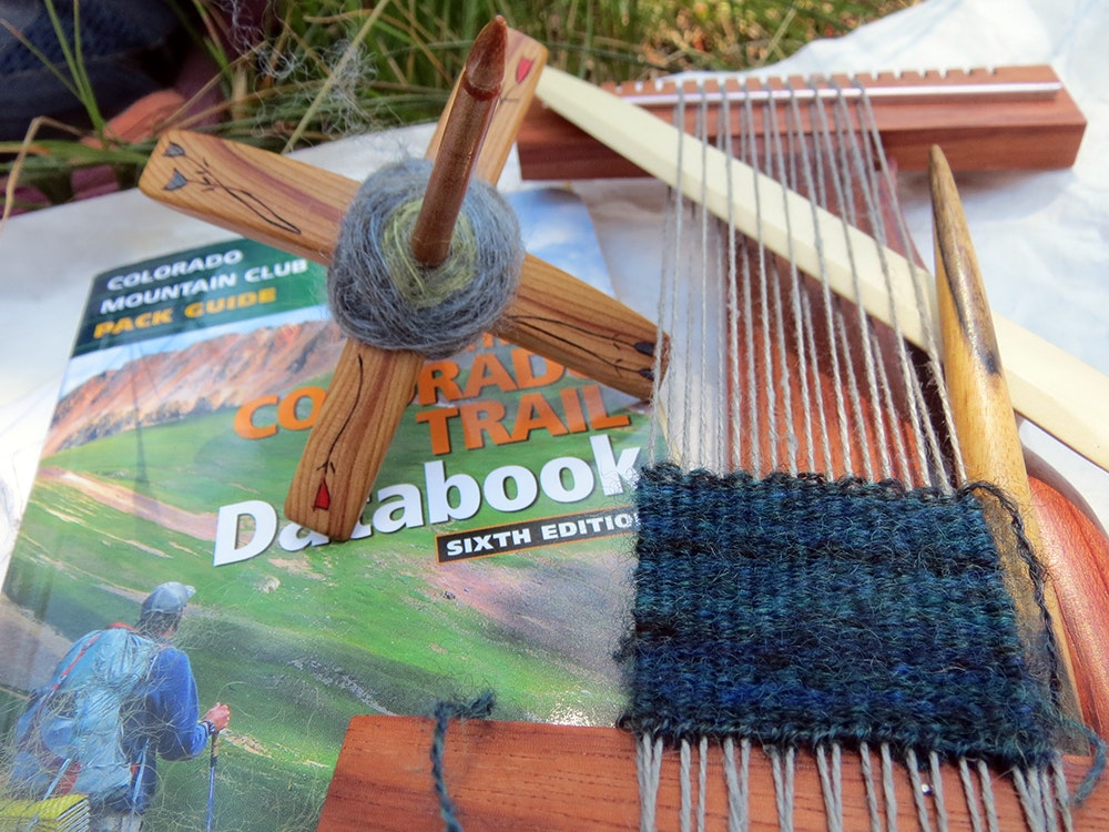 Turkish spindle, small loom with blue tapestry, and Colorado Trail Databook