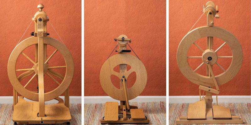 Three spinning wheels in front of an orange wall