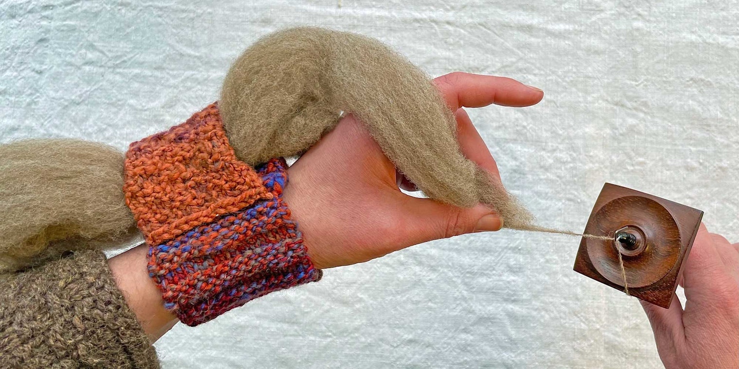 Kate demonstrates how to use the knitted-cuff wrist distaff. Photo by Kate Larson