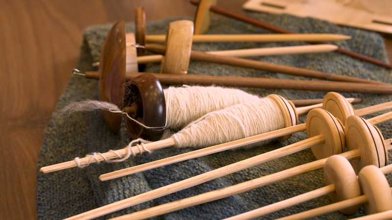 Spindles on a table, some empty and some with yarn