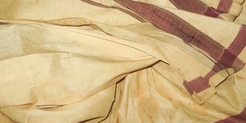 Close-up image of a cream silk dhoti with red border.