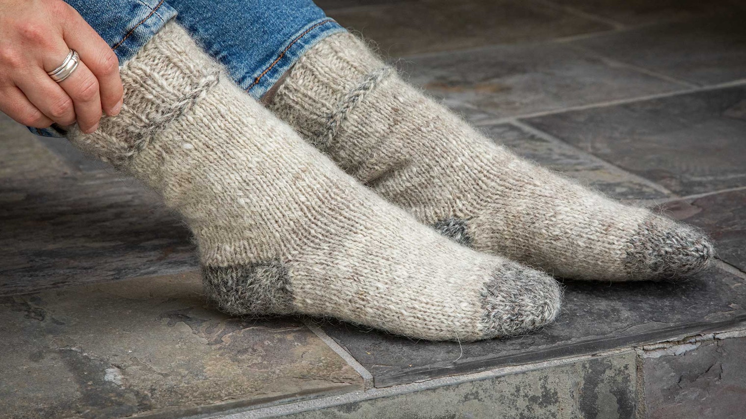 A pair of socks on feet, showing darker gray toes and lighter gray for the foot and leg of the socks.