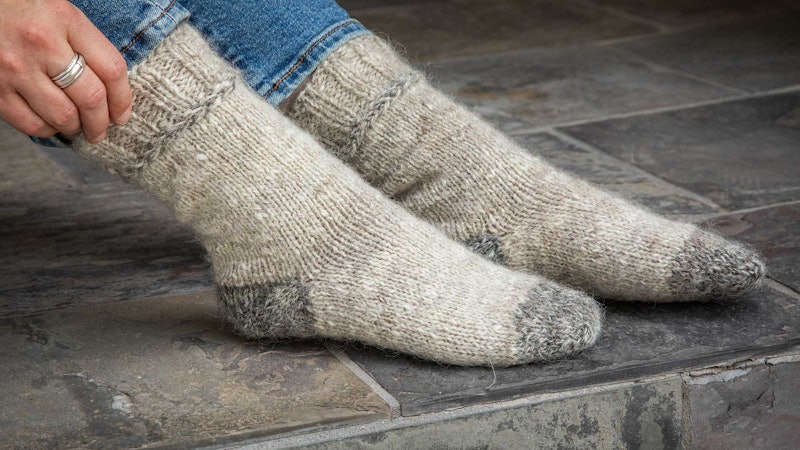 A pair of socks on feet, showing darker gray toes and lighter gray for the foot and leg of the socks.