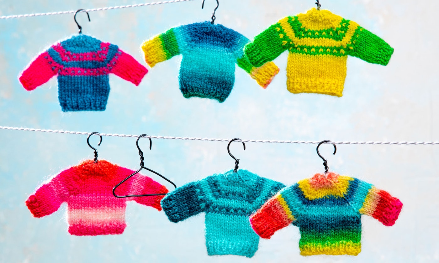 Colorful miniature sweaters hang on a line.