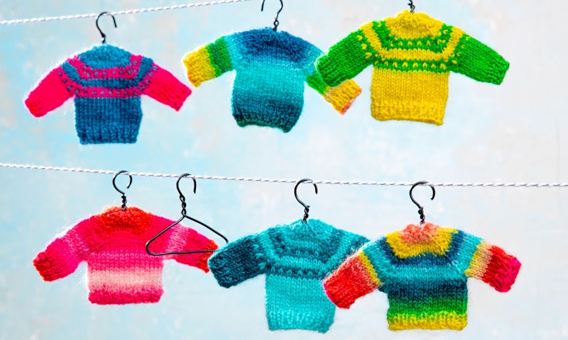 Colorful miniature sweaters hang on a line.