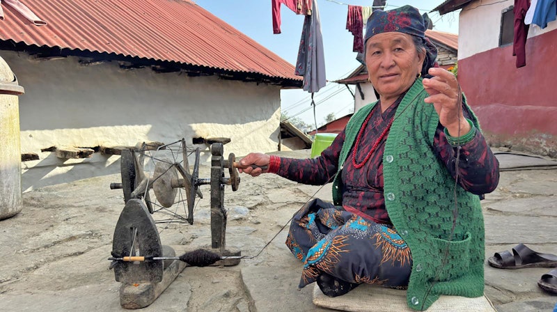 woman in green vest spinning yarn