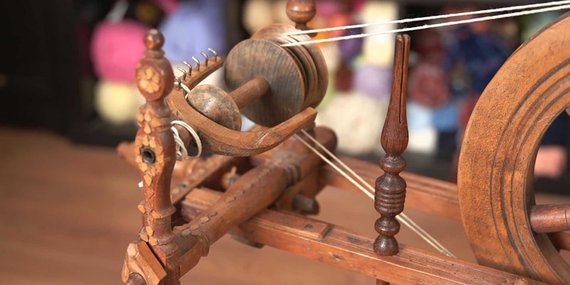 A close-up view of an antique Bavarian spinning wheel with decorative carving.