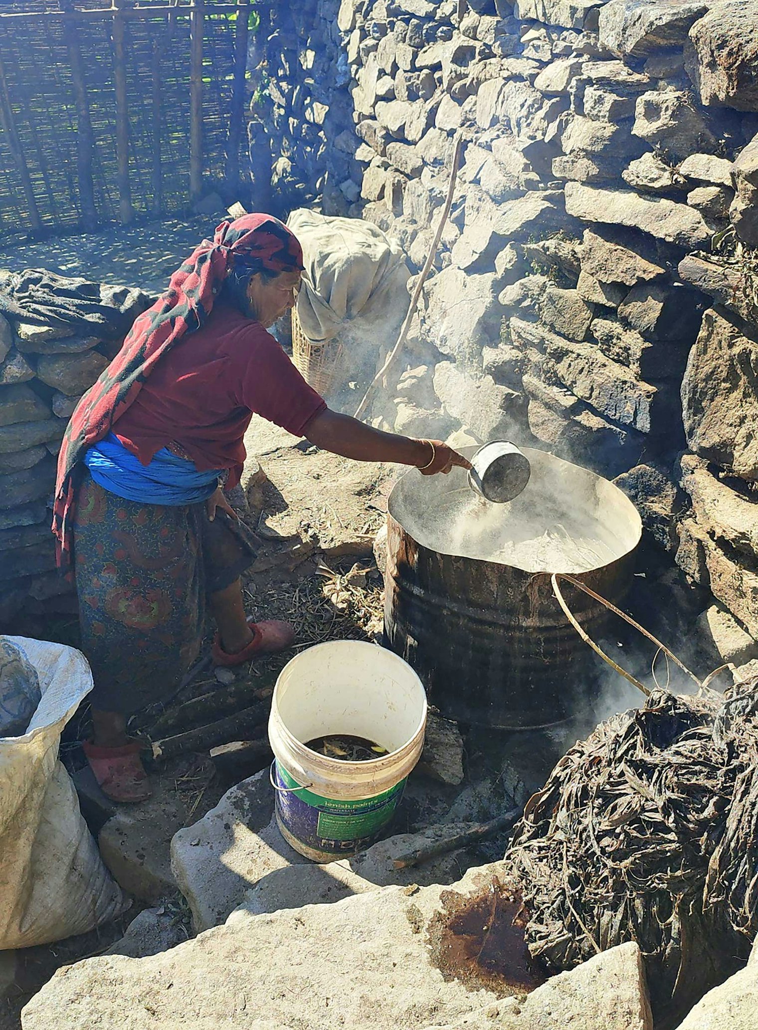 Kho Maya pours ash on top of allo bundles. Photo by Umesh Das