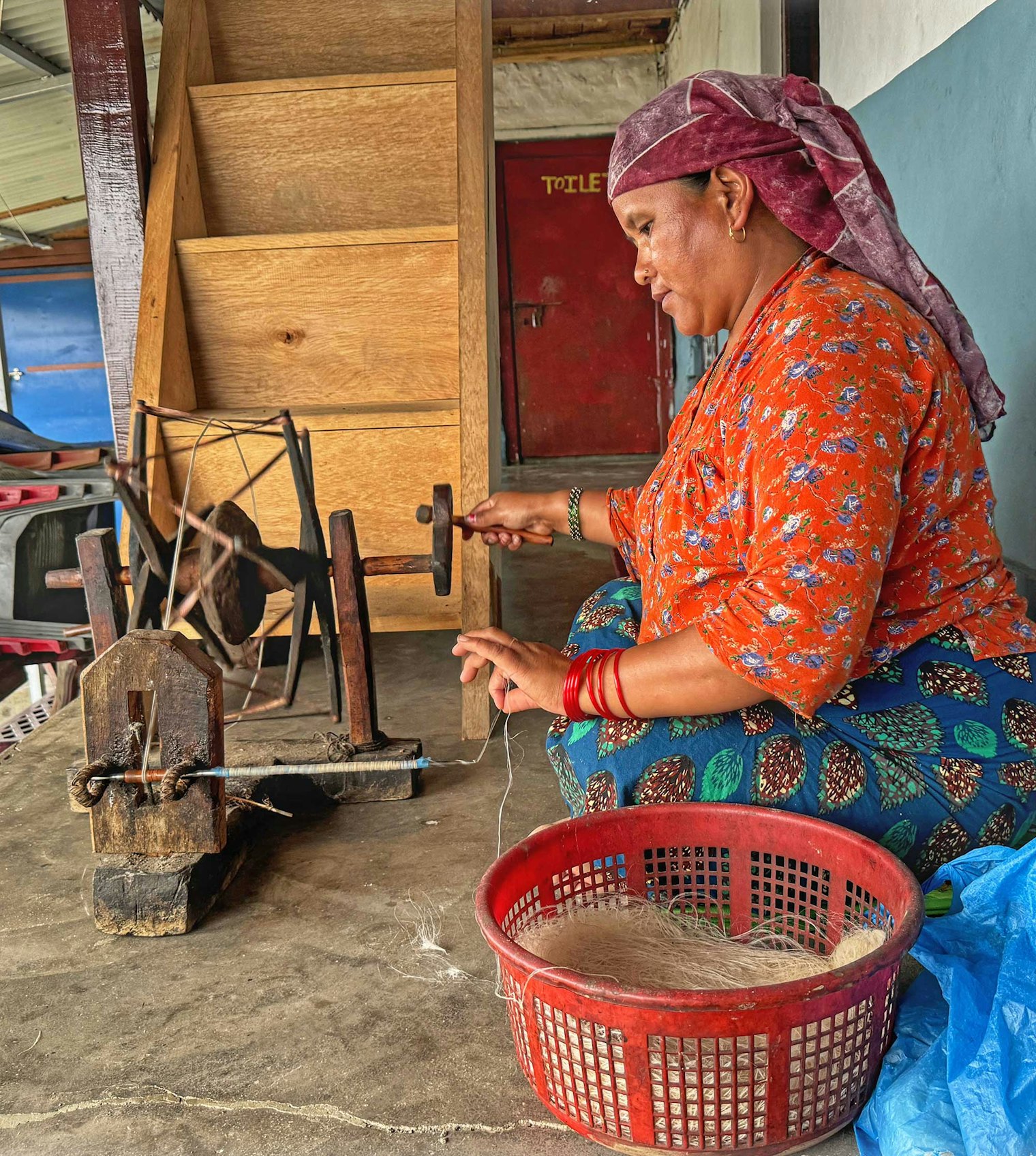 Nau Maya spins nettle thread on a charkha. Photo by Kathleen Mahoney