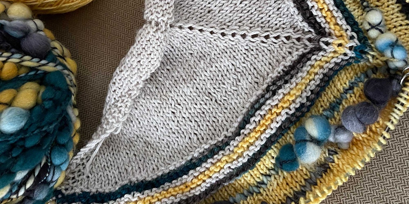 Blue textured yarn knit into portions of a yellow and gray shawl.