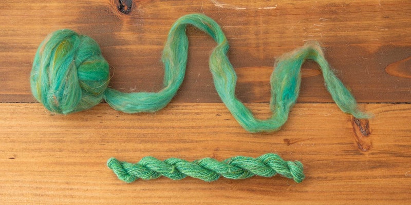 Green fiber and yarn on a wooden background.