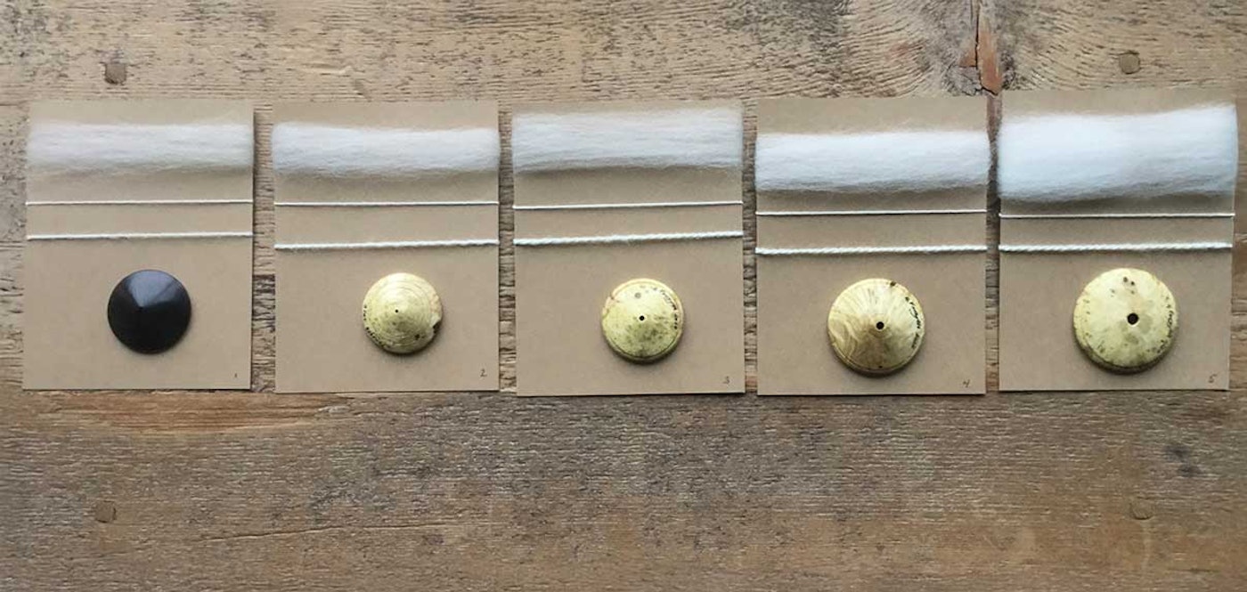 Five dizzes against a wooden surface. Each diz is shown with the sliver pulled from it and the resulting yarn spun from the sliver.