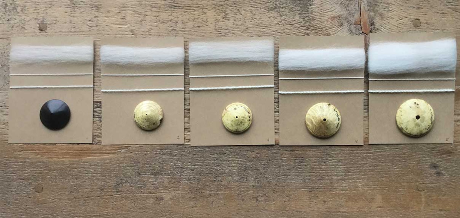 Five dizzes against a wooden surface. Each diz is shown with the sliver pulled from it and the resulting yarn spun from the sliver.