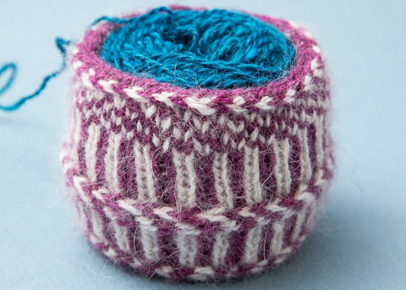 A ball of yarn is protected from raveling by a twined knitted cuff.