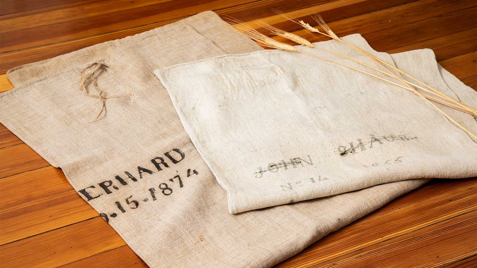 Two antique grain bags on a wooden surface.