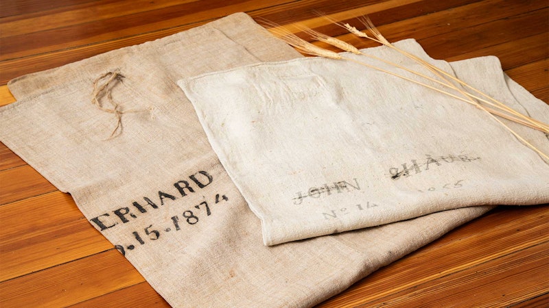Two antique grain bags on a wooden surface.