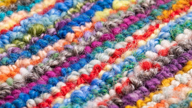 A closeup image of a rug hooked with handspun yarn.