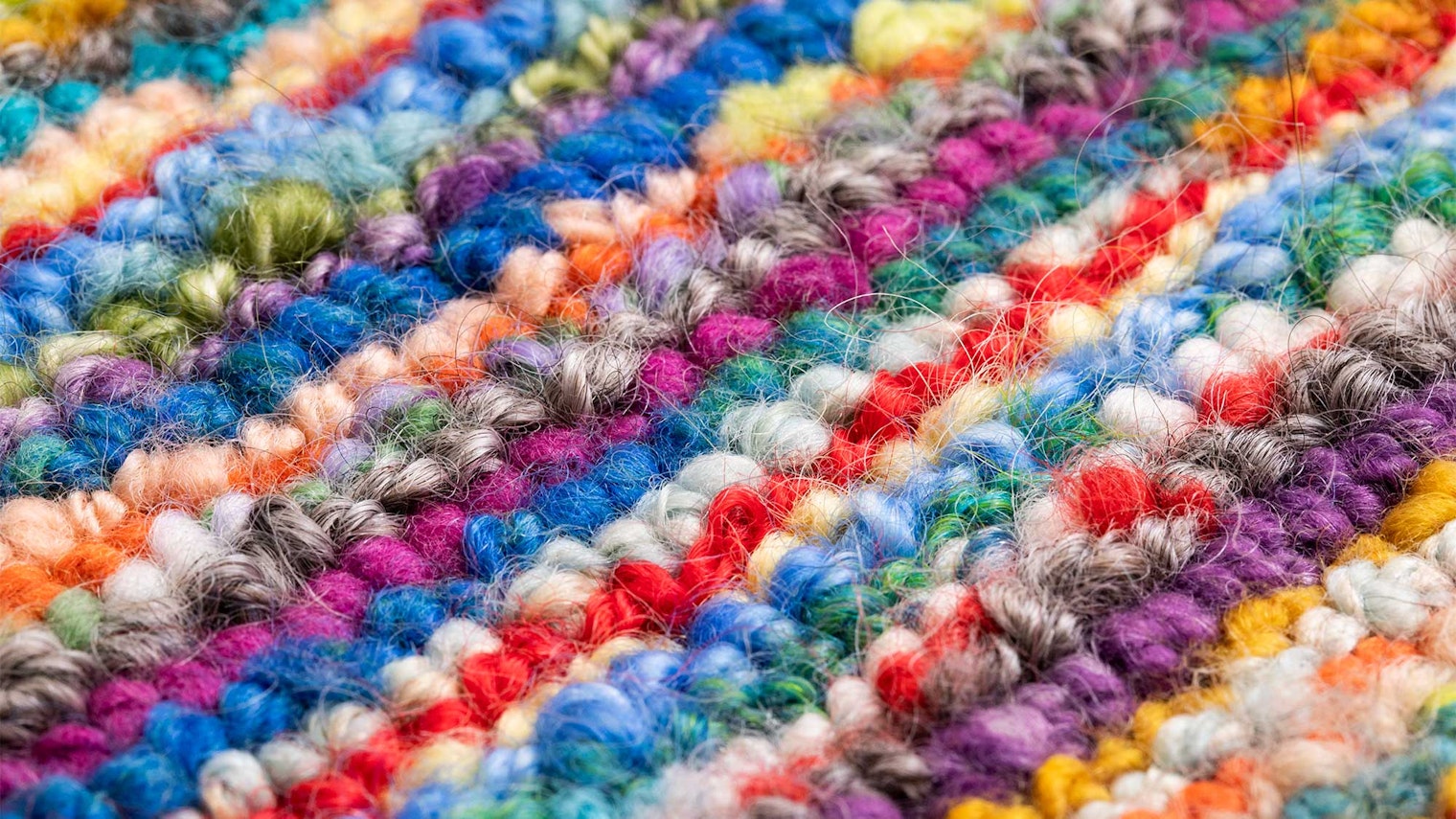 A closeup image of a rug hooked with handspun yarn.