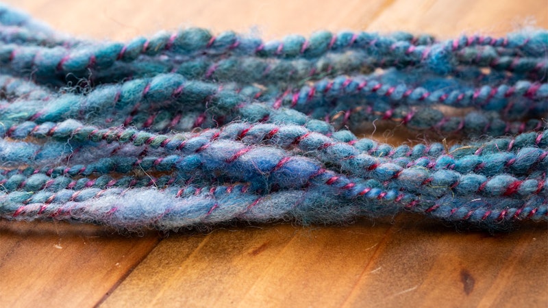 Textured blue and purple yarn on a wooden surface.