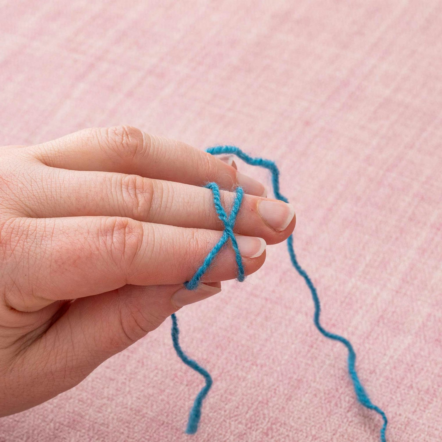 Wrap the long end of the tail around these two fingers one more time so it creates an X shape going over the first loop.