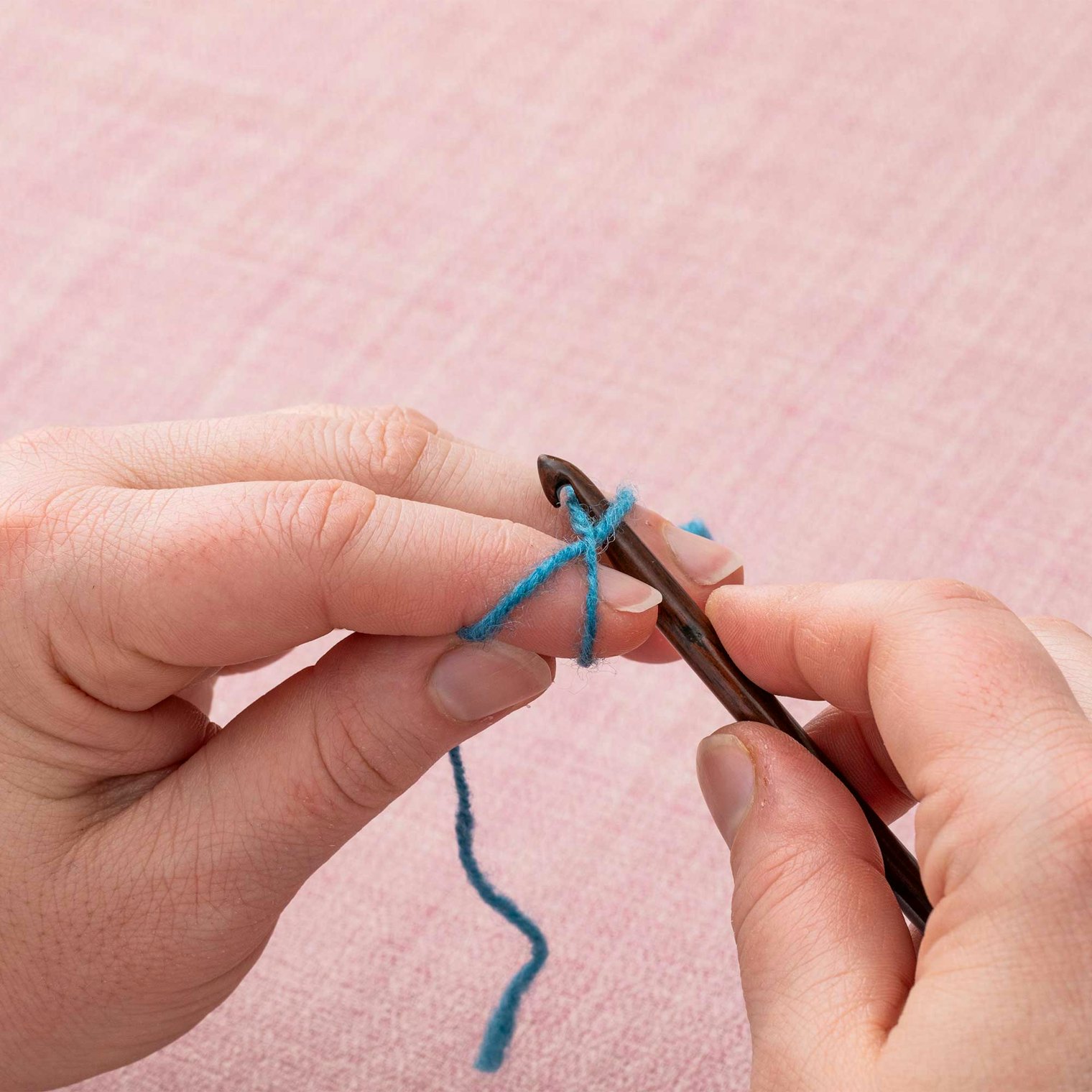 Insert your crochet hook under the top right arm of the X and grab the top left arm of the X with the hook.
