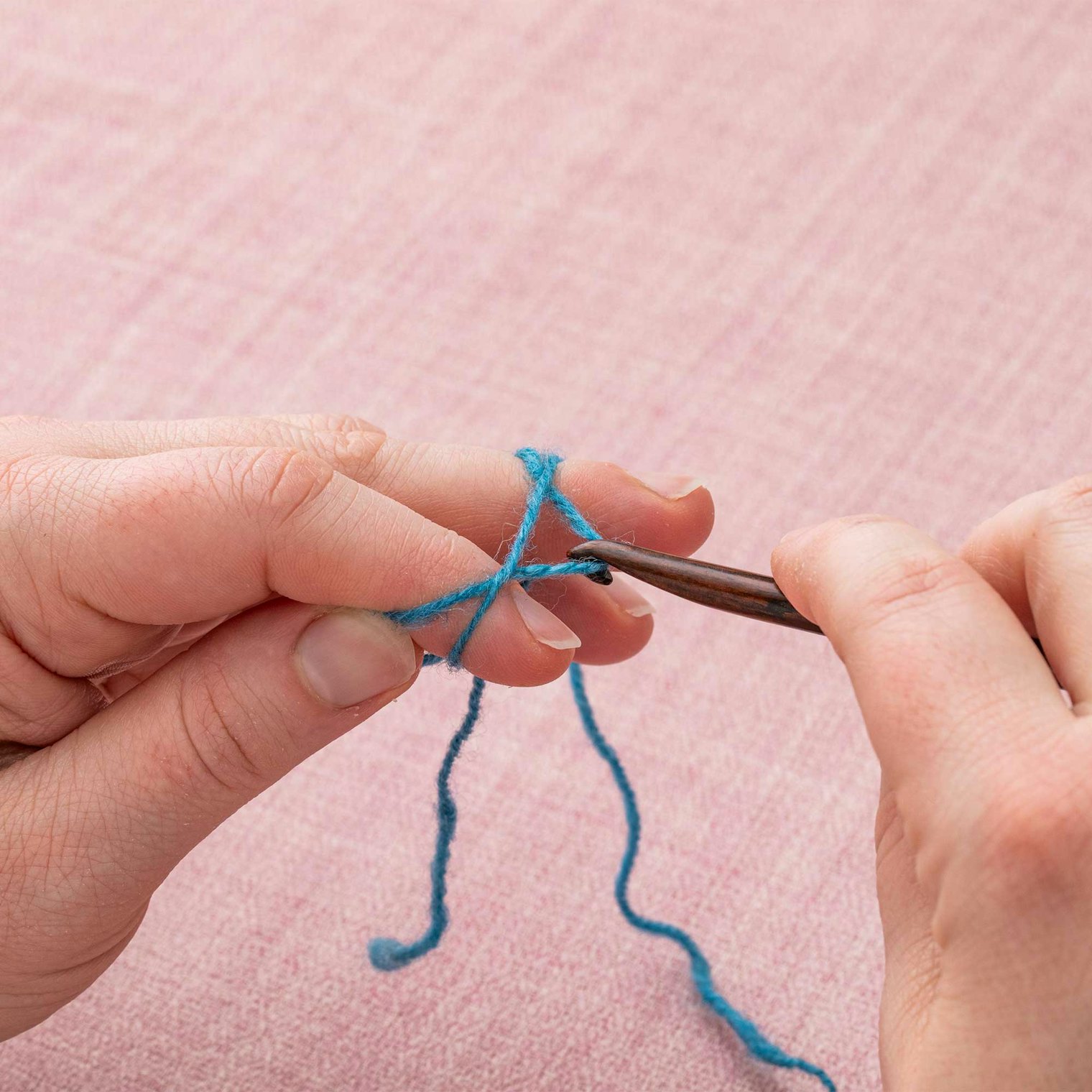 Keeping the working yarn tensioned with your ring finger on the hand holding the magic ring, pull the loop towards your hand holding the hook.