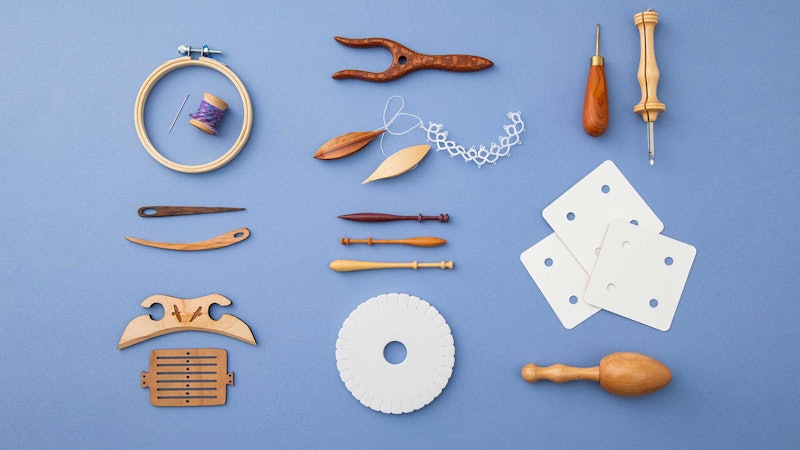 An assortment of fiber arts tools on a blue background.