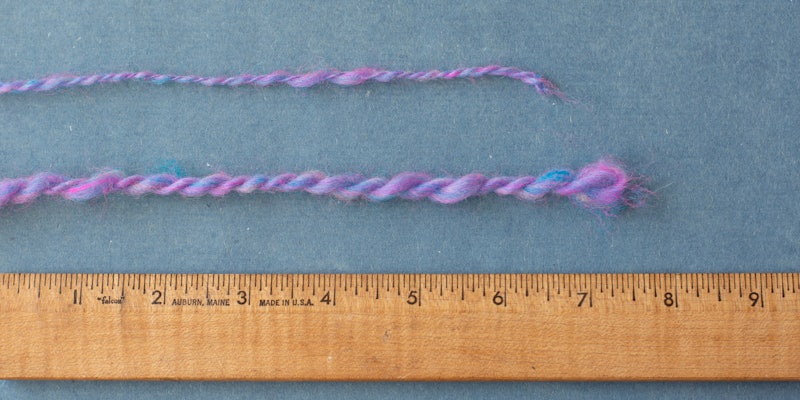 Purple yarns and a ruler on a blue background