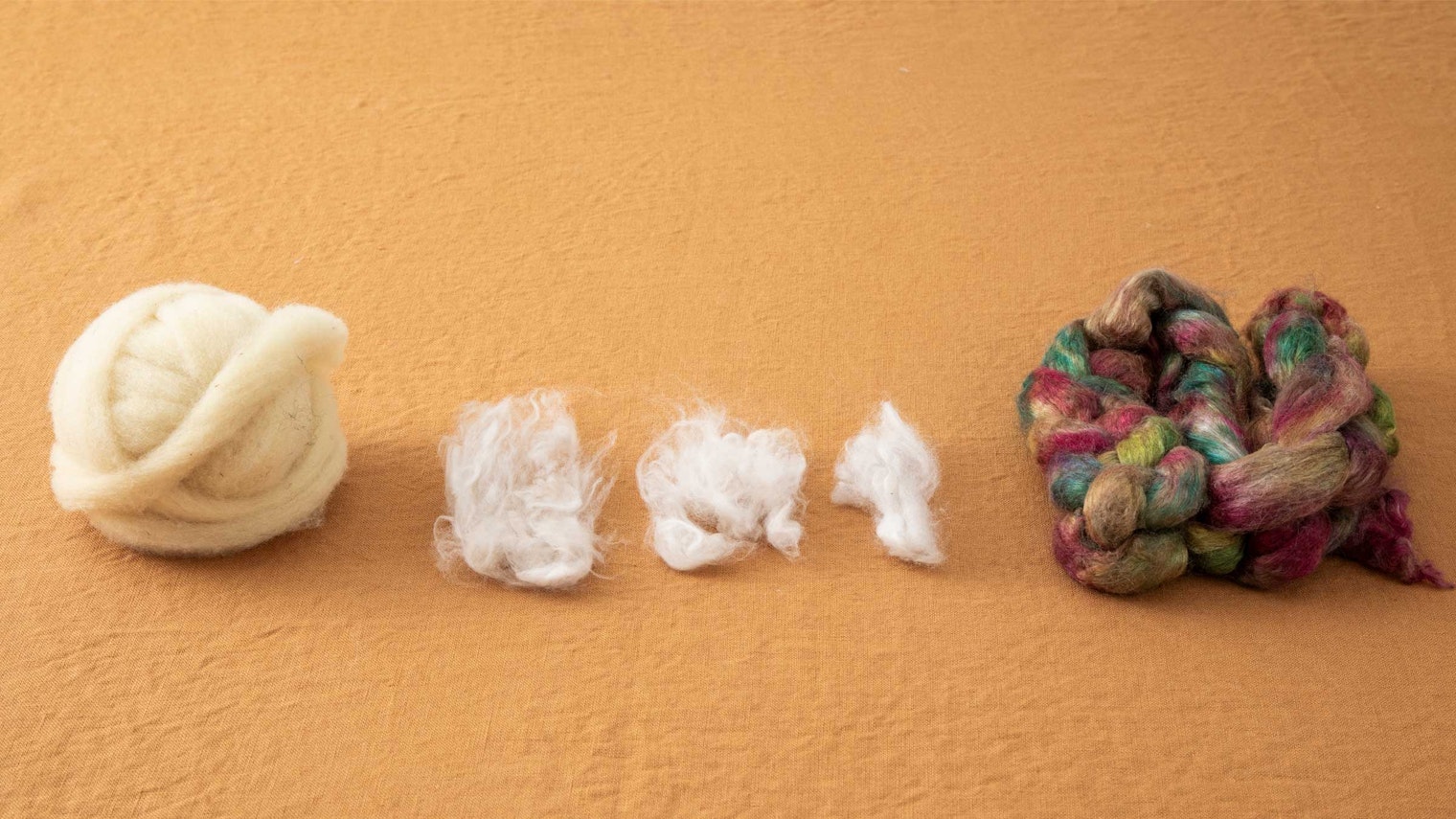 An array of fibers on a marigold fabric background.