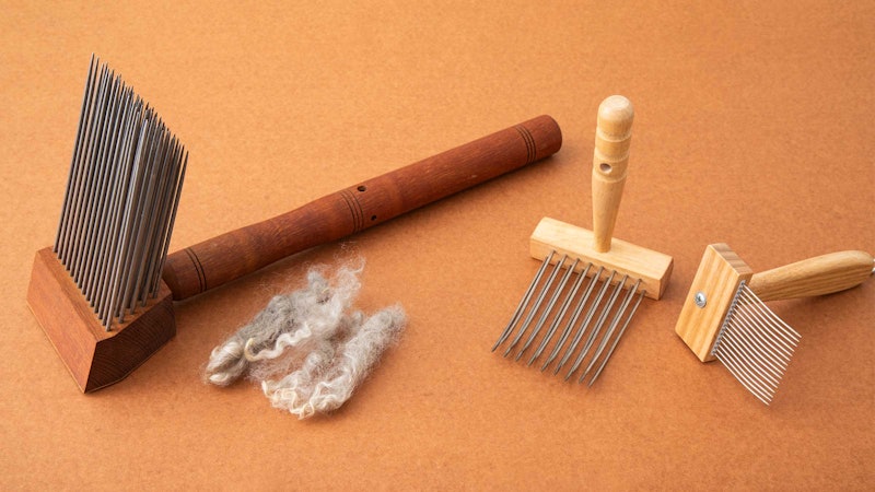 An array of wool combs and wool on an orange background.