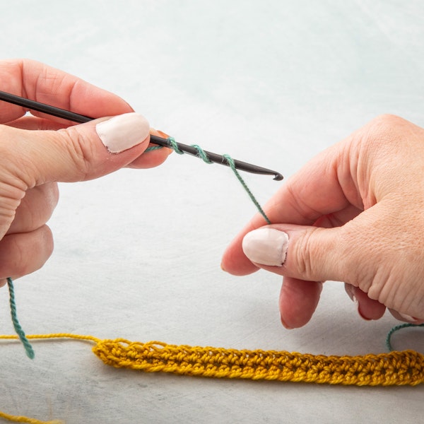 Step 2. Wrap the yarn around your hook the number of required times plus one for the stitch you are working; in this example, a double crochet. The first wrap is to anchor the yarn, the second wrap is the acting loop on the hook and the third wrap is for a double crochet.