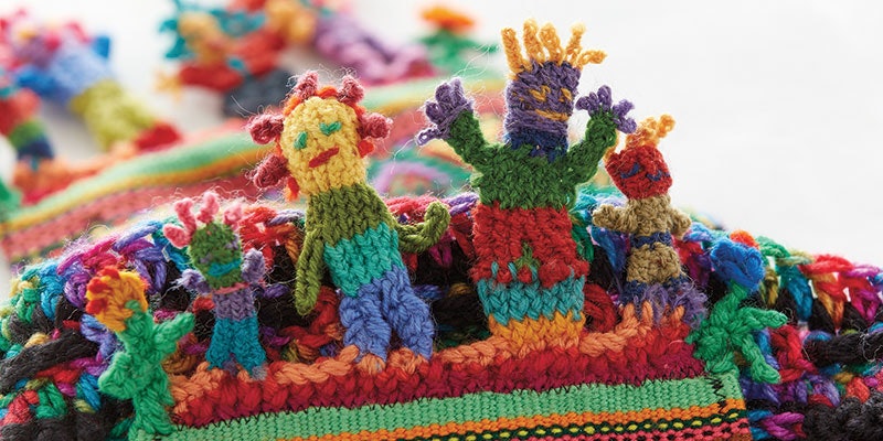 Detail of scarf designed and made by Barbara Morrison from a found woolen knitted piece, embellished with ribbon and trim, with cross-knit looping figures in wool.