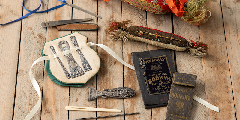 A collection of antique bodkins and various commercial and handmade bodkin holders, as seen in PieceWork Summer 2022. Photo by Matt Graves