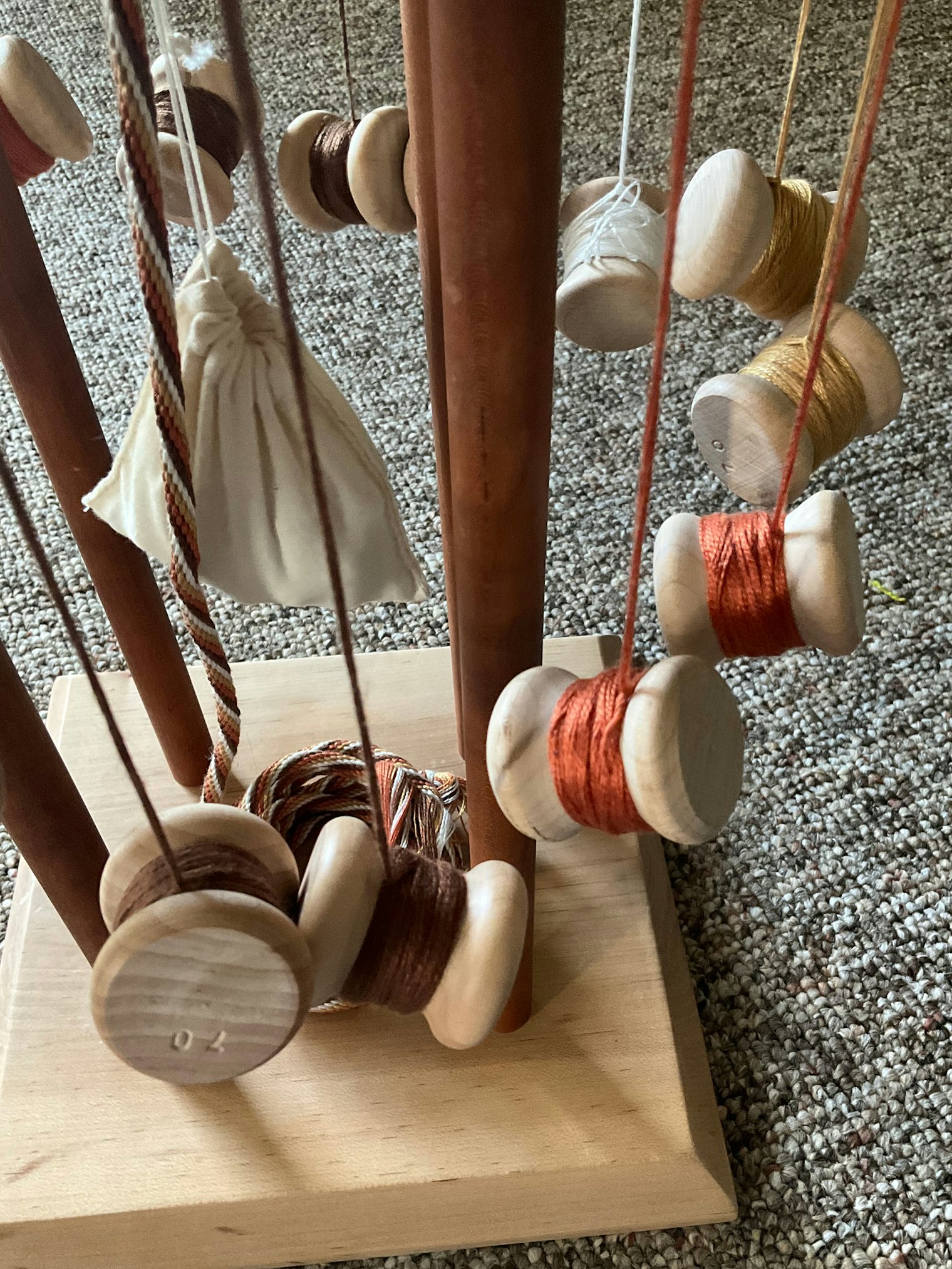 Weighted tamas hold the threads for braiding. The finished cord has a counterweight attached to balance the tamas and is shifted along the cords as it grows.