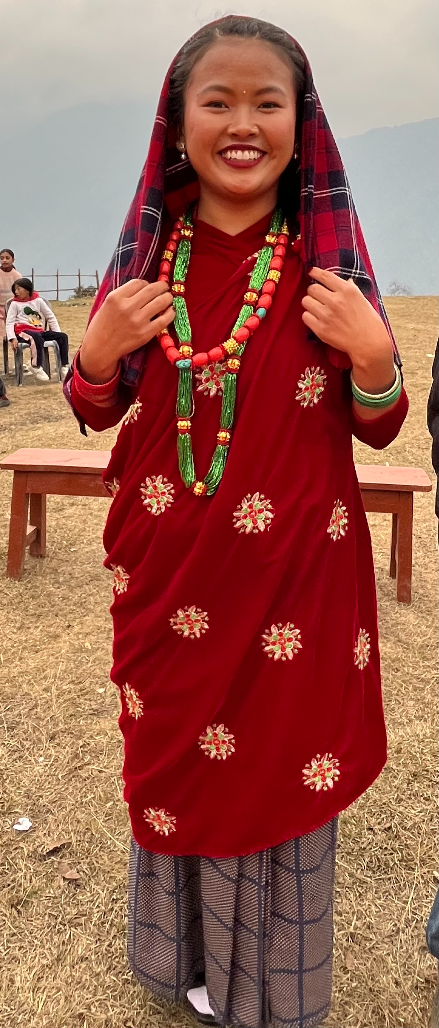 A young woman prepares to dance at the International Women's Day celebration in Ghandruk. She drapes a tartan pachauri over her head for warmth.