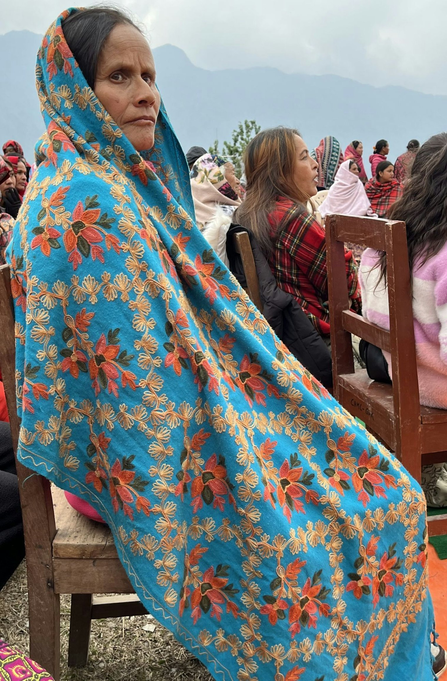 A woman in Ghandruk drapes a heavily embroidered Aari-style pachauri over her head and shoulders to keep warm during a festival celebration.