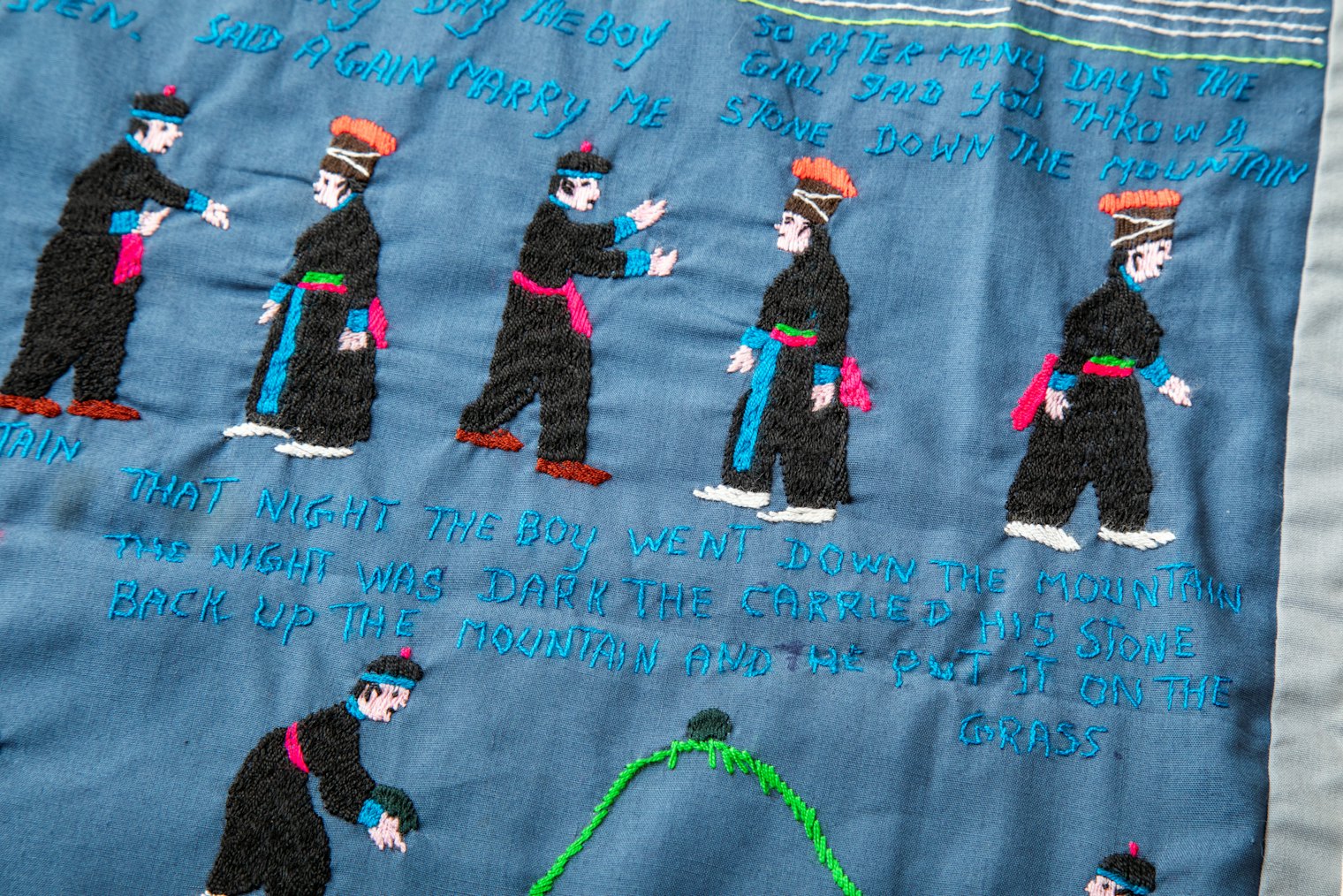 This story cloth scene shows the brother and sister discussing the marriage and the brother placing a stone on the hill.