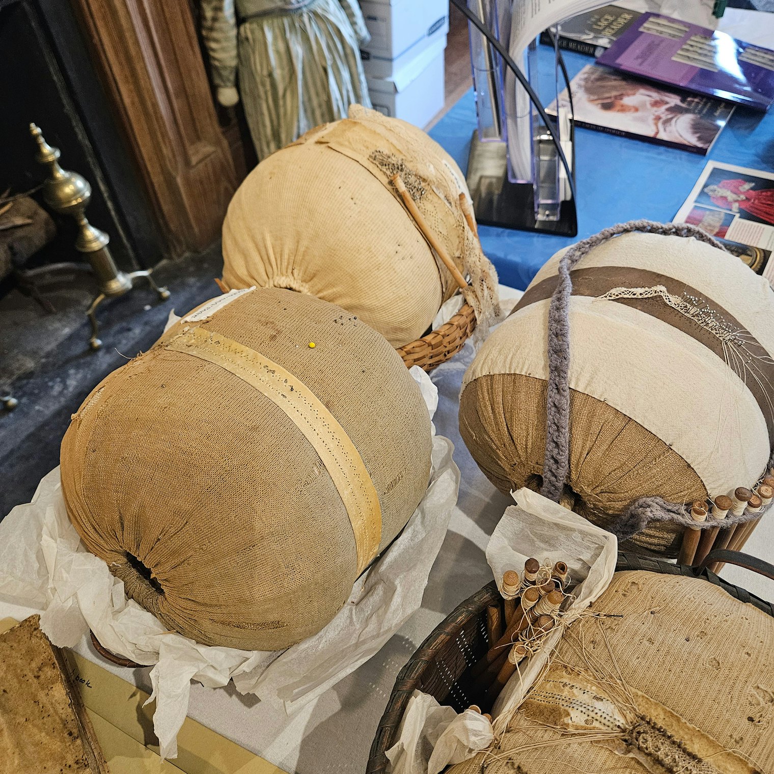 The Ipswich Museum holds several original pillows, patterns, and bobbins from the active era of lacemaking. Bolster style pillows with patterns wrapped around the entire circumference for continuous work on yards of lace are seen here. Typically, pillows were stuffed with the local salt marsh grass, and lacemakers used linen or silk thread with locally produced bobbins to make lace. 