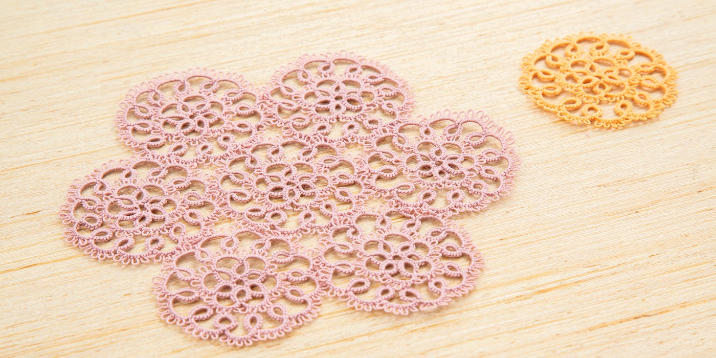 Two tatted lace motifs, a smaller orange one at the top right, and several combined shown in light pink thread.