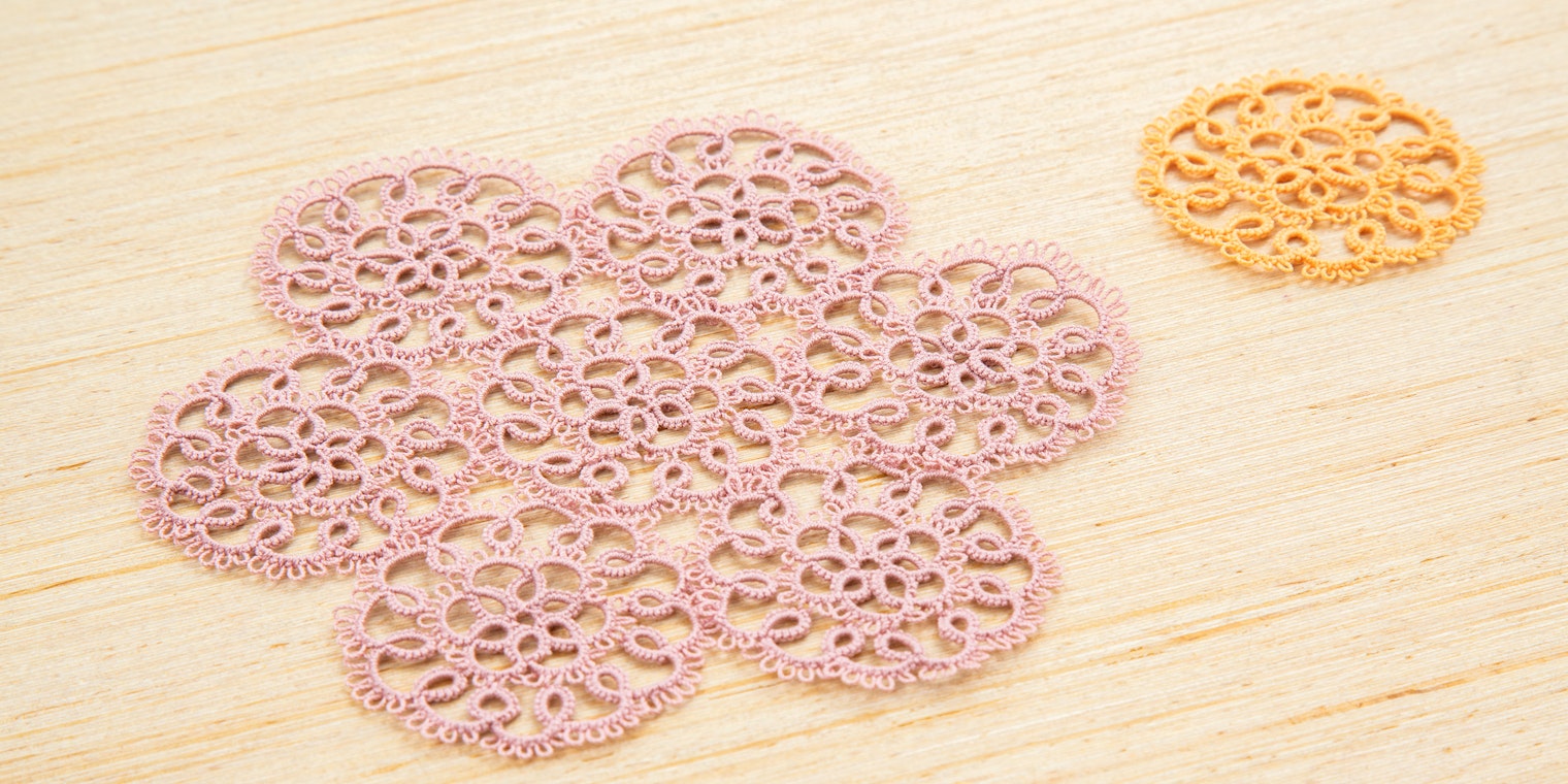 Two tatted lace motifs, a smaller orange one at the top right, and several combined shown in light pink thread.