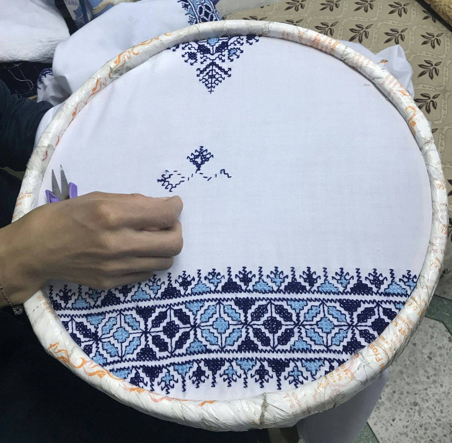 An embroidery artist stitches traditional fessi embroidery at a shop in the old medina in Fes, Morocco.