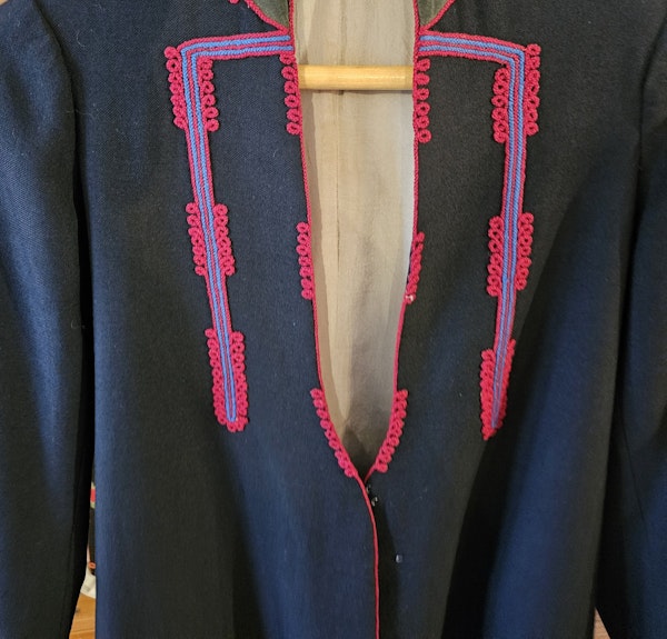 Detail of a traditional black wool outer coat embellished with loops of bright red cord displayed at the Heimtali Museum. Photo courtesy of the author