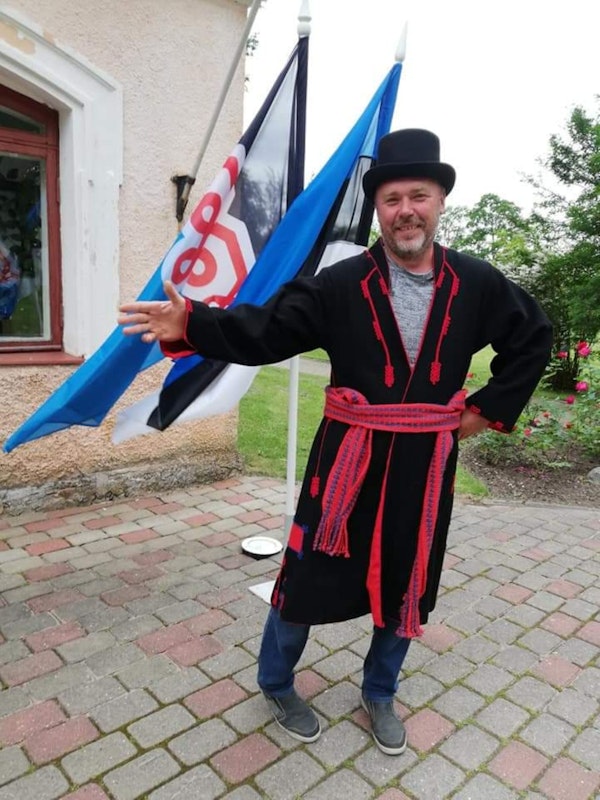 Estonian man in a traditional Mulgi coat with the flag in the background. Photo courtesy of the Mulgi Elamuskeskus—Mulgi Experience Center