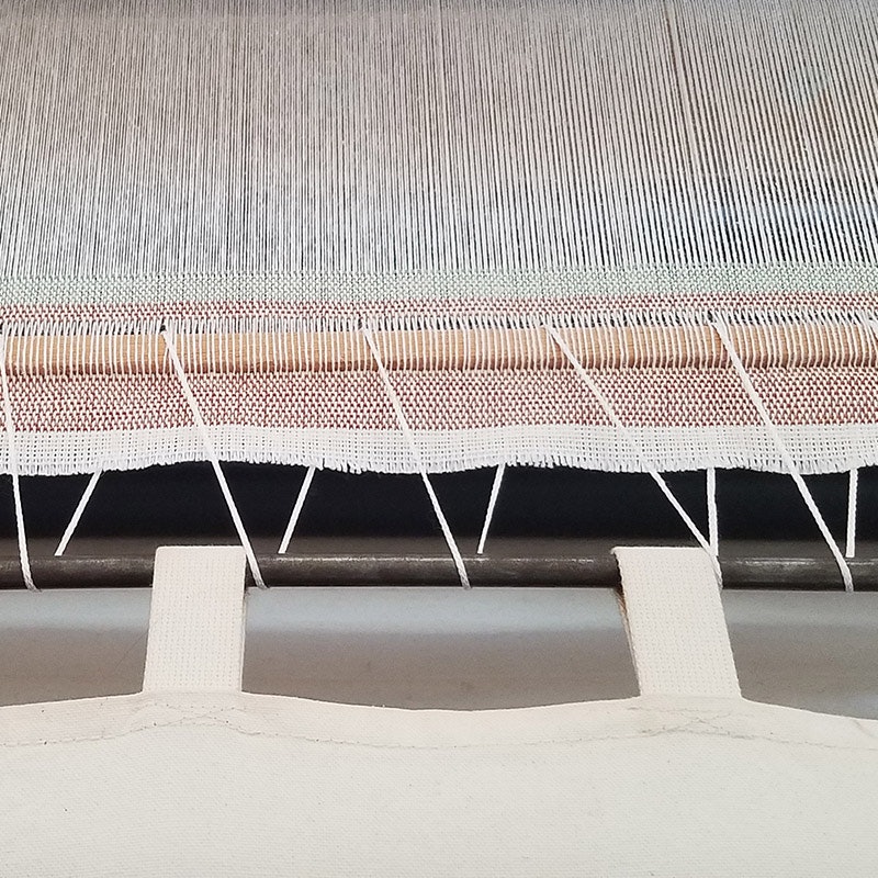 To cut off pieces before a warp her warp was done, Susan wove in a stick and lashed it to the cloth apron.