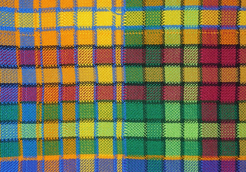 A colorful scarf sample with half woven with cool colors, and the other half warm colors
