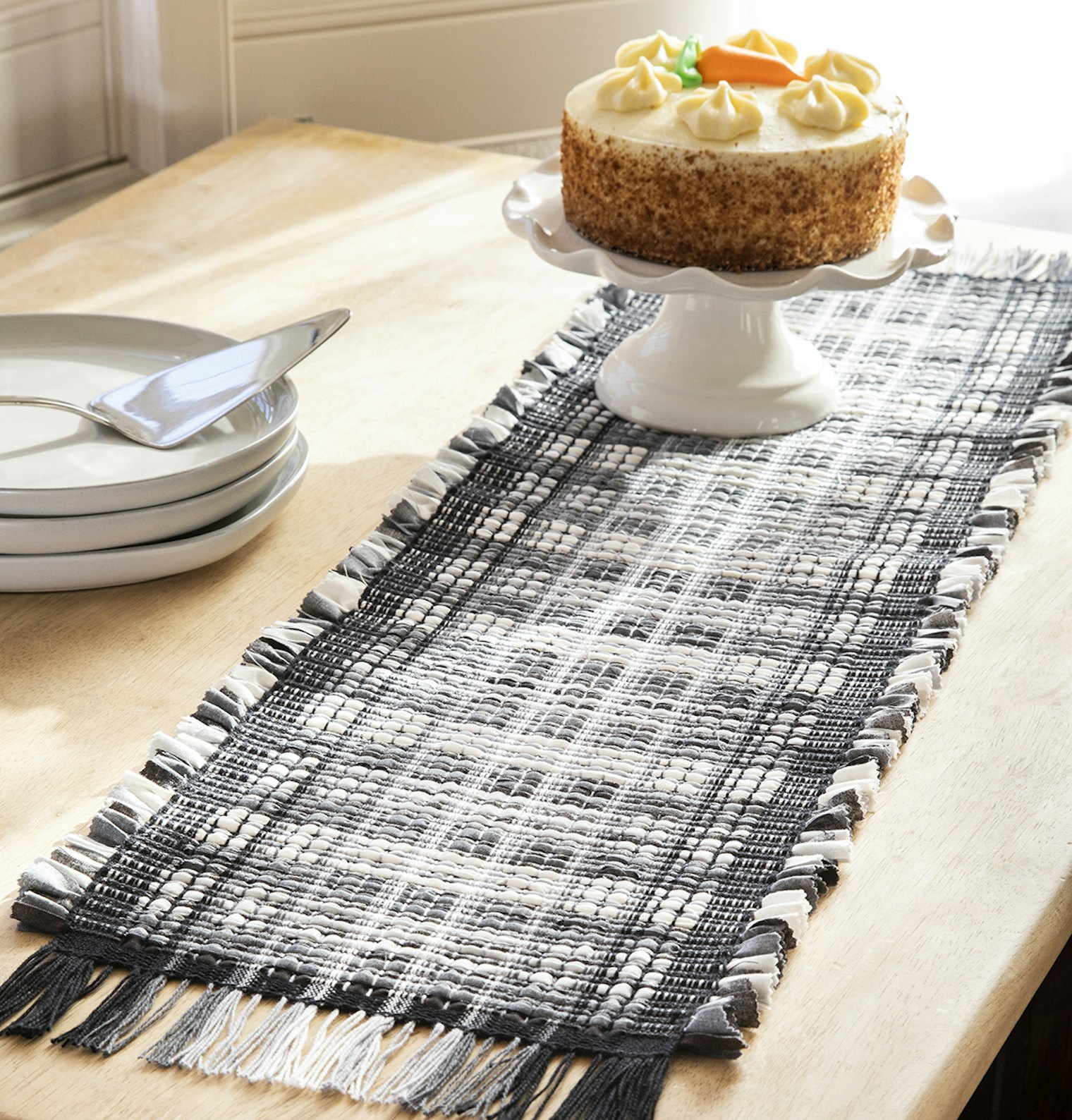 A runner with shades of white and grey sits atop a table.