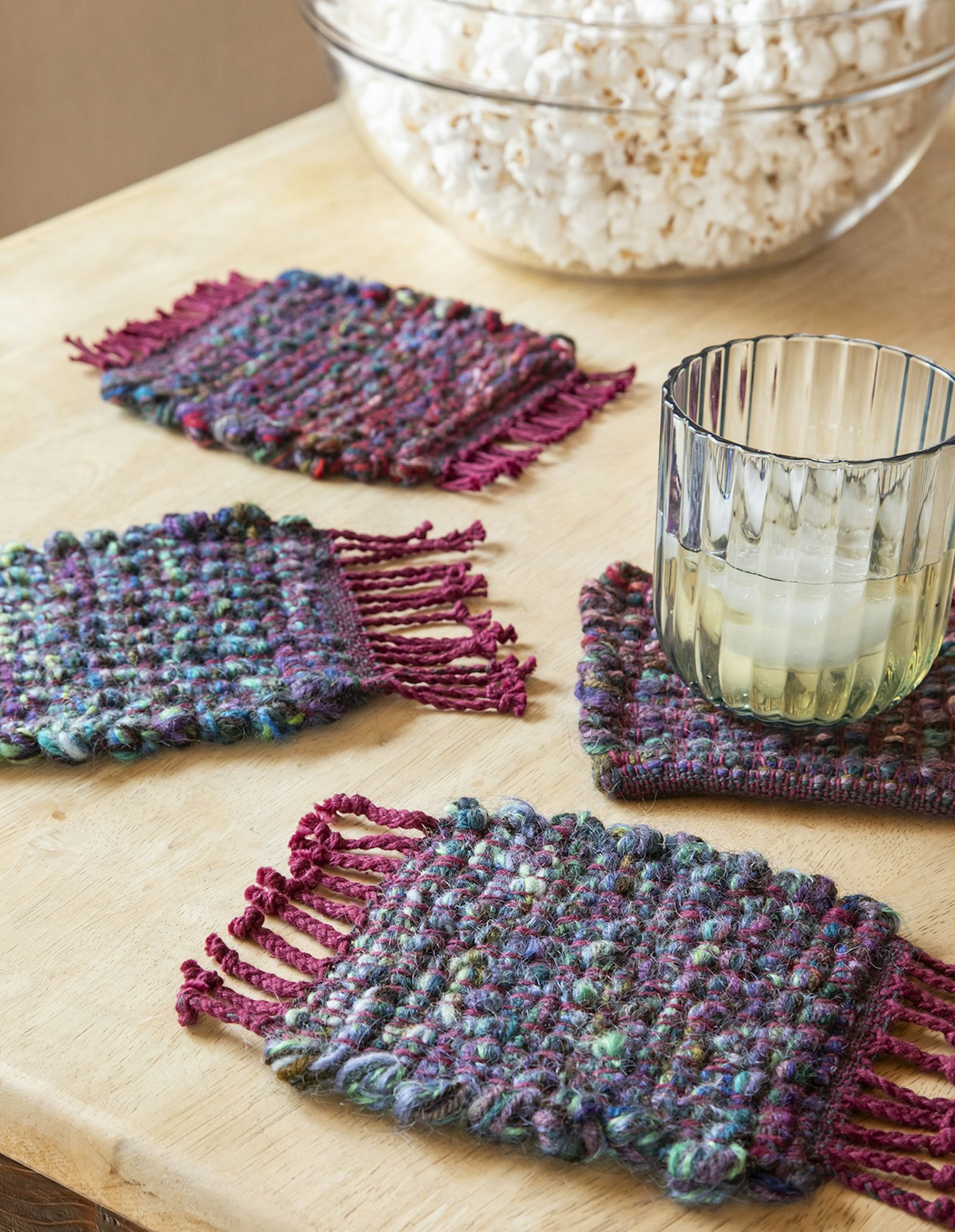 Four coasters woven in shades of blue with deep red.