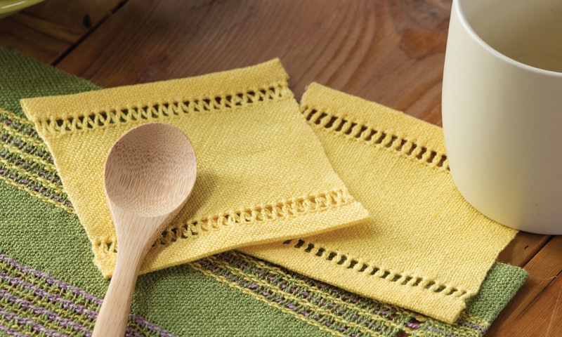 Two yellow handwoven mug rugs with fancy hemstitching