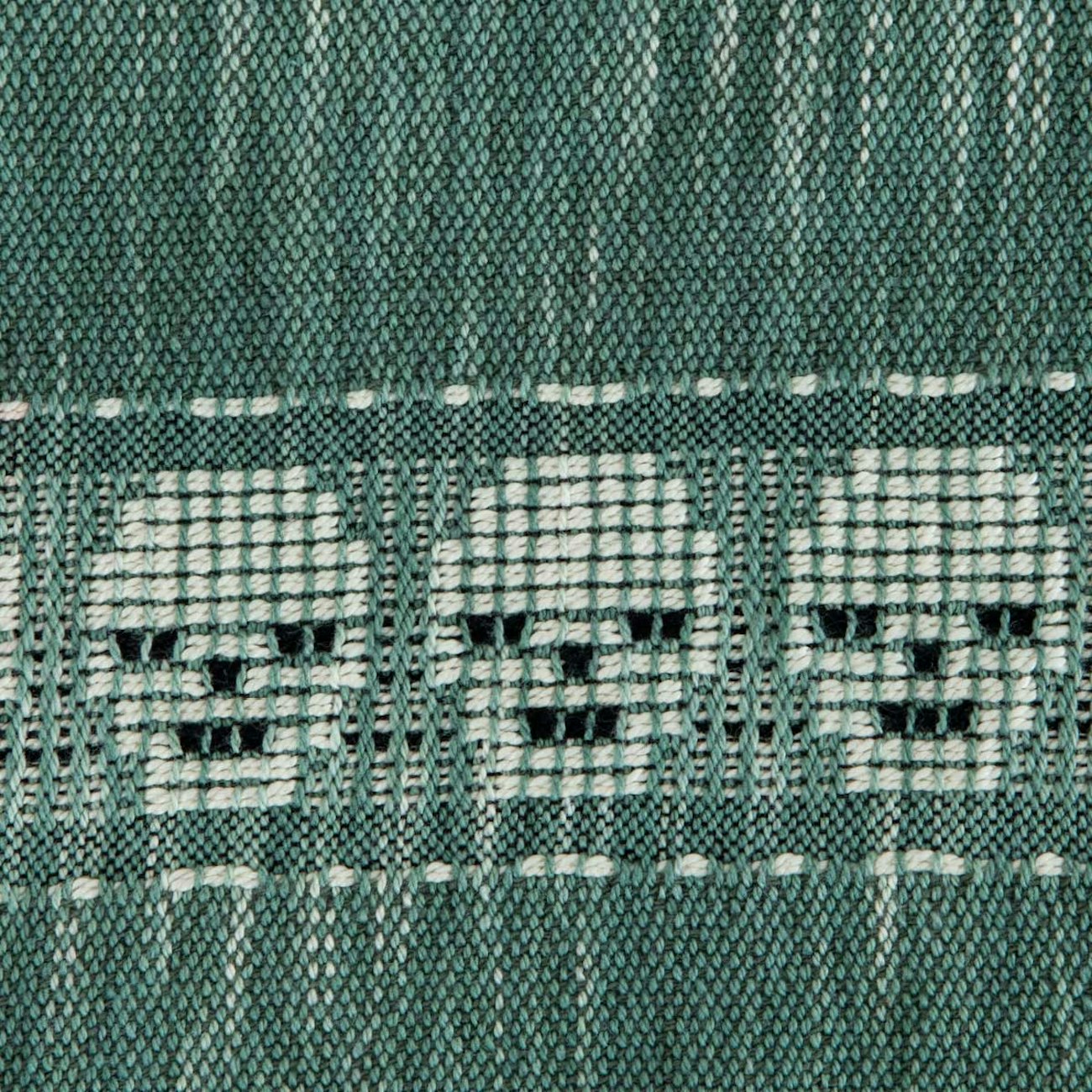 A variegated green textile with a series of white skulls.